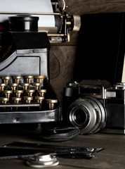 Vintage retro typewriter and analog film camera on brown wood table background - journalism or writer concept, selective focus