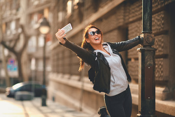 Young happy woman tourist taking selfie on the street in europe city