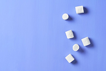 Lot of scattered white marshmallows cylindrical form lies on purple scratched concrete table. Space for text. Top view