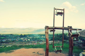 Wooden swing chair on the mountain with village in the valley over sky in Pai Mae Hongson, Thailand