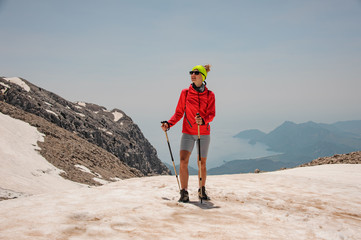 Girl standing on the dirty snow on the Tahtali mountain with hiking sticks