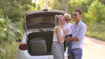 Portrait of happy family getting ready for road trip and summer vacation. Happy family with luggage near car. Traveling concept. Beginning of the trip.
