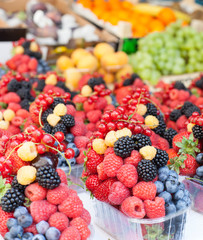 boxes with ripe, juicy, bright berries and fruits laid out in a row in the market, store. close up, vertical frame