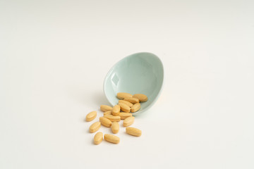 Yellow vitamin pills on white background