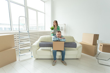Cheerful young couple rejoices in moving to a new home laying out their belongings in the living room. Concept of housewarming and mortgages for a young family