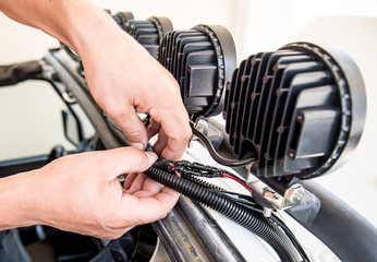 view of the hands of a mechanic inserting electrical wires of roof lights into a protective plastic sheath, upgrading vehicule © Danieduverger