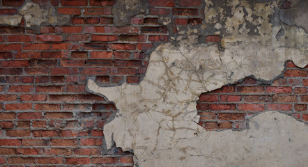 The unique texture of the old brick wall and beige, falling off plaster with dirty strokes of concrete