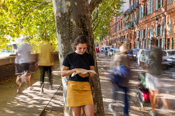 young woman reading in the street 