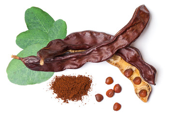 Carob beans with powder. Healthy organic sweet carob pods with seeds and leaves on white background. Top view - obrazy, fototapety, plakaty