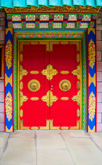 Colourful and ornate red door at the entrance to a Buddhist temple.