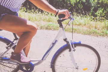 Naklejka premium Pretty Young Woman Riding Bicycle In The Park Rear View