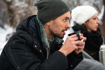 Young man enjoying hot tea in nature during winter