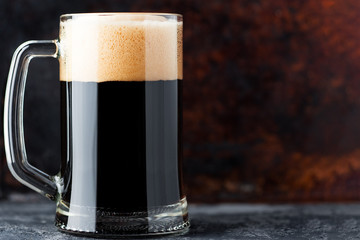 Full glass mug of dark beer on a rusty background