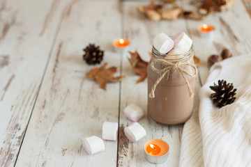 Hot chocolate cacao drink with marshmallows and cinnamon on wooden background.