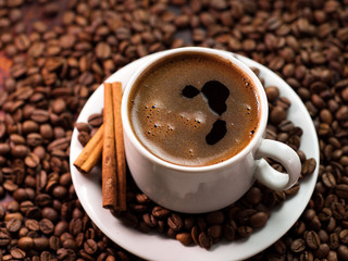 White Cup of espresso coffee on roasted Arabica coffee beans