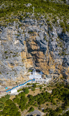 Aerial view of The Monastery of Ostrog, Serbian Orthodox Church situated against a vertical background, high up in the large rock of Ostroška Greda, Montenegro. Dedicated to Saint Basil of Ostrog 