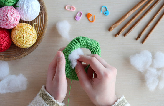 Making crochet pyramid from colored rings. Toy for babies and toddlers to learn mechanical skills and colors. On the table threads, needles, hook, cotton yarn. Handmade crafts. DIY concept.
