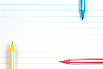 Colorful striped pencils on notebook lined paper background with copy space. Back to school, education, learning concept