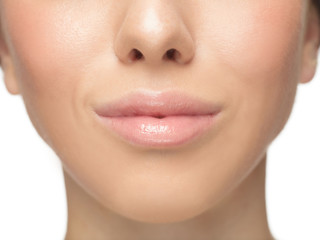 Close up shot of well-kept female big lips and cheeks on white studio background. Smiling, looks pretty good. Concept of women's health and beauty, self-care, body and skin care.