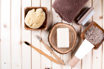 Zero waste bathroom accessories, natural brush, oil, sea salt, hair brash, toothbrush, towel on wooden background