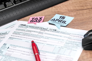 Tax form with pen, calculator, mouse, keyboard on wooden background