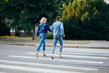 Back view of young happy couple running crosswalk in the street