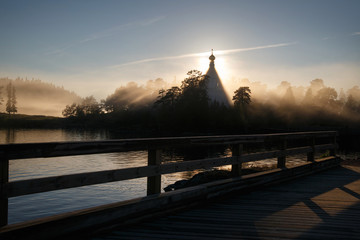 Morning foggy landscape with a silhouette of the church in the sun's rays, Valaam, Karelia, Russia.