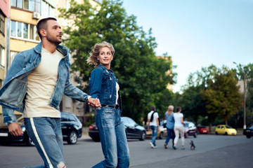 Obraz premium Young happy couple running crosswalk in the street