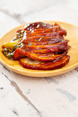 Chinese lacquered pork slices with its caramelized sauce prepared for eating in a wooden plate
