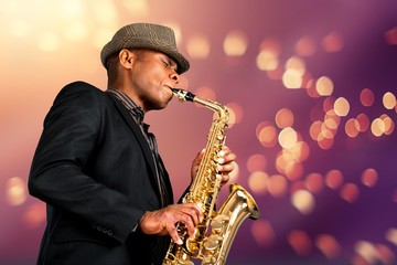 Close-up man playing on saxophone on blurred background