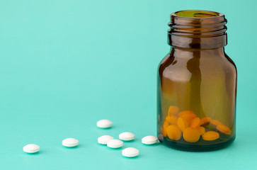 White round tablets scattered near glass bottle of pills