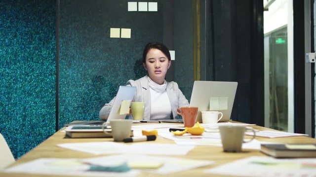 exhausted young asian woman working overtime in office