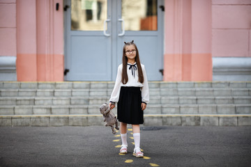 Child girl with plush toy against school background. Back to school. Selective focus.