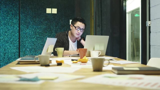exhausted young asian man working overtime in office
