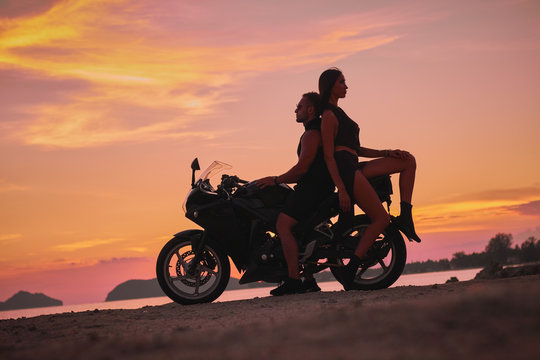 romantic couple watching sunset on motorcyclist