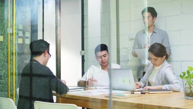 group of young asian entrepreneurs discussing business in company meeting room