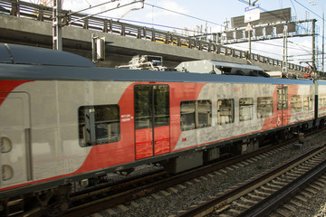 Fototapeta premium a view of railroad tracks and riding a red train car next to the freeway in Moscow Russia