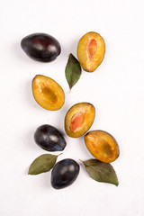 Composition of fresh plums with leaves on light background. View from above.