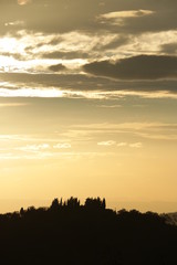 Landscape of the Tuscan hills. Sky with clouds at sunset. Cypres
