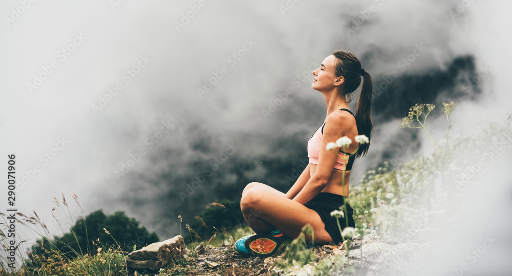 Wall mural woman meditating on mountain cliff above the clouds. alone travel healthy lifestyle. healthy life co - Wall murals