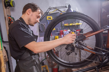Fototapeta na wymiar Service, repair, bike and people concept - Mechanic repairing a mountain bike in a workshop
