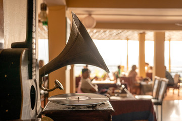 Old gramophone, guitar and people in restaurant, focus on gramophone, closeup