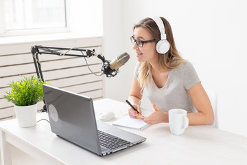 Radio host concept - Woman working as radio host sitting in front of microphone over white...