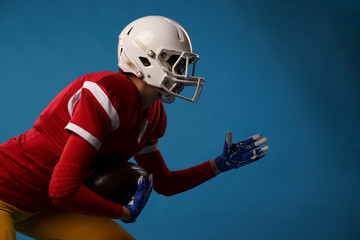 Side view of running sportswoman of american football player on blue background.