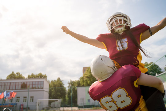 Image of two American football sportswoman wearing helmets with their hands to side against cloudy sky