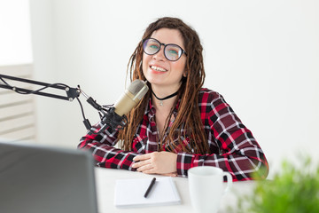 Broadcast, music, dj and people concept - woman with dreadlocks and glasses working at the radio