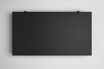 Blank black minimalistic cardboard paper list with stationery clips at light background, copyspace.