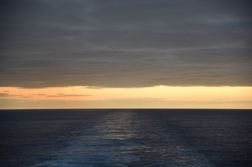 Fototapeta na wymiar Sunset over the sea, view from the sailing cargo ship.