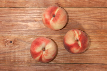 Three tender ripe peaches on a wooden table. Copy space.