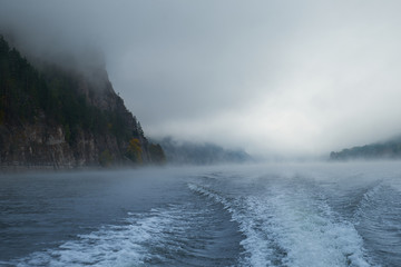 Walk on the Norwegian lake on a boat in the autumn in the fog. Wake of the boat